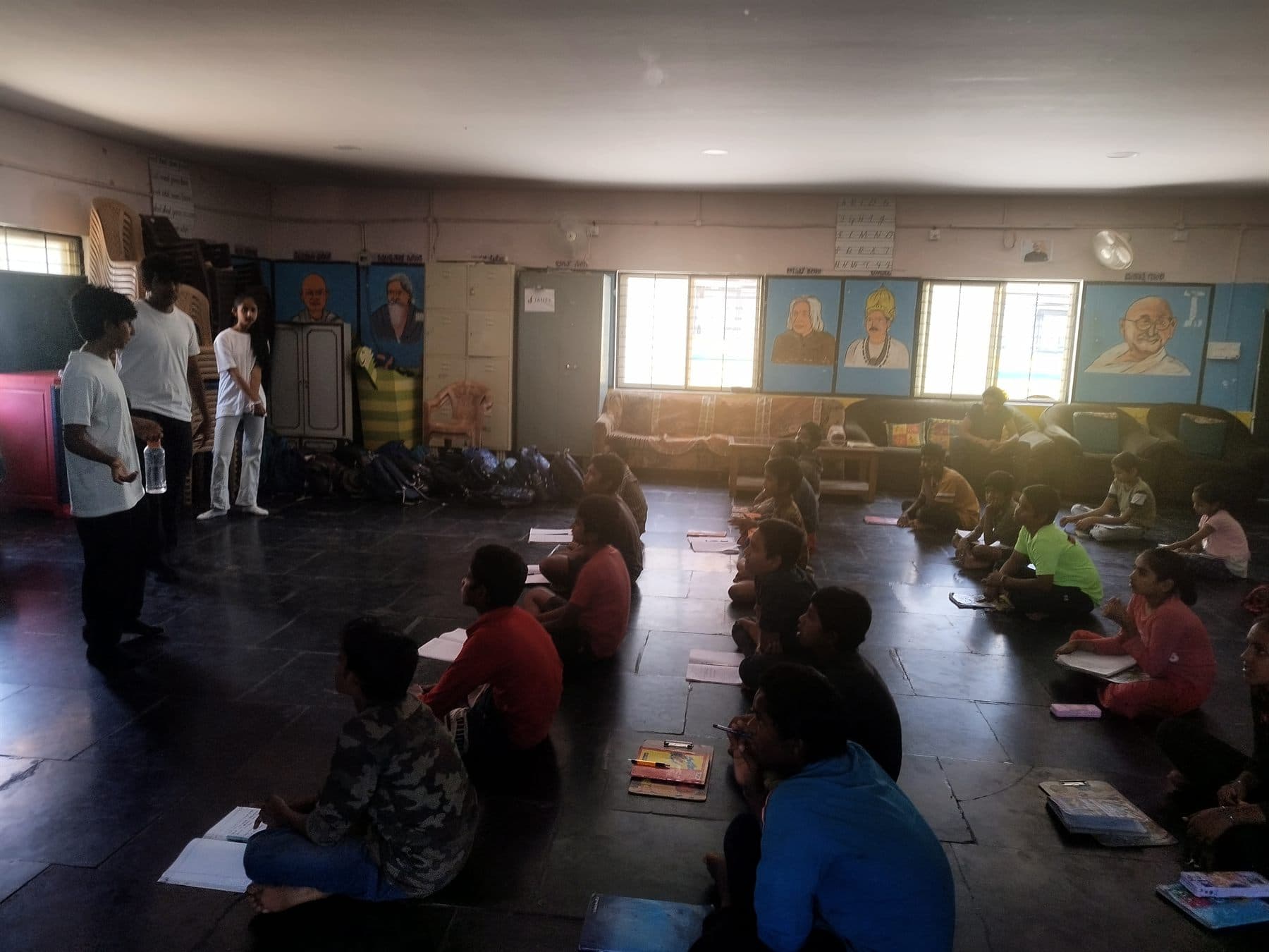 Volunteers introducing a session to students seated on the floor